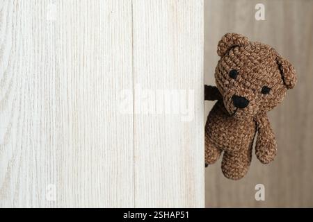 Ours jouet mignon jetant un coup d'œil hors de la planche de bois. Espace pour le texte Banque D'Images