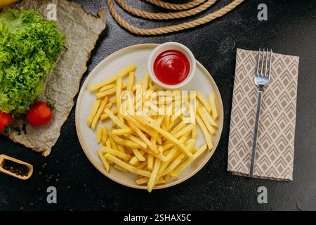 Frites dorées croustillantes accompagnées de ketchup, servies sur une assiette dans un cadre élégant Banque D'Images
