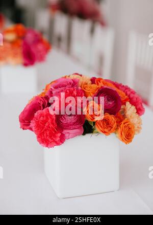 Une collection vibrante de fleurs dans des tons roses et oranges rehausse la table pour une célébration. Banque D'Images
