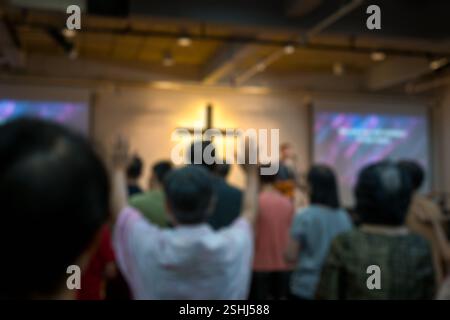 Vue arrière du culte chrétien avec les mains levées dans l'église. Flou artistique, adapté à l'arrière-plan. Banque D'Images