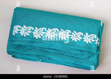 Beau saree en coton bleu-vert fait à la main plié sur un fond en bois clair. Beaucoup de femmes bengali portent des sarets tous les jours, ainsi que pour les occasions spéciales l Banque D'Images