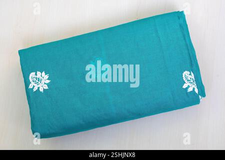 Un beau saree en coton bleu-vert fait à la main est plié sur un fond en bois clair. Beaucoup de femmes bengali portent ces sarees tous les jours, ainsi que sur o spécial Banque D'Images