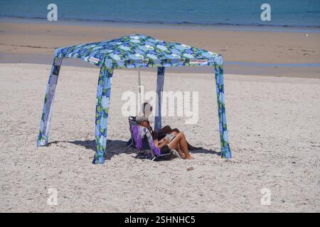 Adélaïde, Australie, 11 février 2025. Les amateurs de plage se baladent sous un belvédère de plage sous le soleil chaud dans la banlieue de Grange. Un avertissement de vague de chaleur « code rouge » a été émis pour les parties de l'Afrique du Sud dont les températures devraient atteindre 40 °c. Crédit. Amer Ghazzal/Alamy Live News Banque D'Images