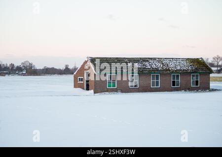 Dans la campagne est cette ancienne grange en pierre debout. La terre est couverte de neige pendant l'hiver Banque D'Images