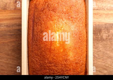 Gâteau éponge au citron espagnol fraîchement cuit dans un plateau en papier biodégradable sur une surface en bois. Dessert méditerranéen traditionnel. Vue de dessus Banque D'Images