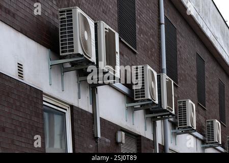 Plusieurs unités de climatisation sont installées à l'extérieur du mur d'un bâtiment résidentiel. Ces unités fournissent le refroidissement par temps chaud, mettant en évidence une comm Banque D'Images