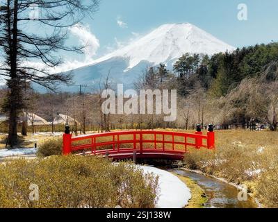Mont Fuji recouvert de neige au Japon au début du printemps. Paysage japonais typique avec Fujisan emblématique et pont rouge traditionnel au premier plan. Banque D'Images