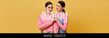 Deux superbes sœurs jumelles s'embrassent de manière ludique, mettant en valeur leurs tenues élégantes et leurs sourires éclatants. Banque D'Images