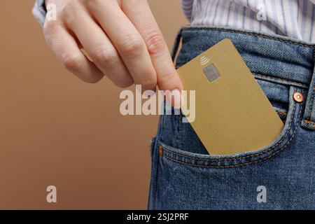 Croisé gros plan de femme habillée dans des vêtements décontractés tenant la maquette de carte bancaire de crédit dans la poche de Jean, Banque D'Images