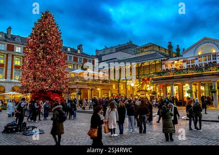 Les gens se rassemblent autour du grand arbre de Noël à Covent Garden, un centre commercial et de divertissement dans le West End de Londres, Londres WC2 Banque D'Images