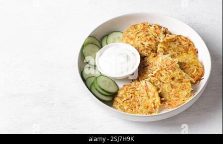 Crêpes croustillantes au chou avec crème sure et tranches de concombre frais sur assiette blanche Banque D'Images