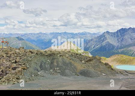 Une vue panoramique sur les pics alpins accidentés près de Samnaun, en Suisse, avec des pentes herbeuses et un sentier sinueux sous un ciel partiellement nuageux. Banque D'Images