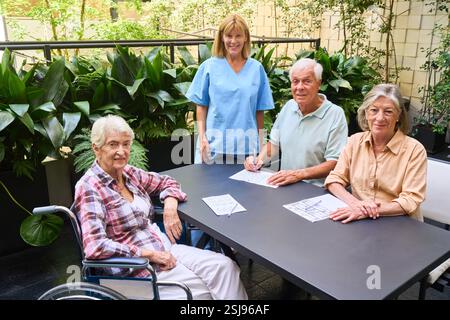 Les résidents âgés participent à des activités récréatives et thérapeutiques avec l’aide du personnel dans un environnement serein. Cela représente la communauté des aînés Banque D'Images