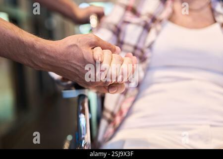Un moment de bienveillance capturé en gros plan où un soignant apporte un soutien émotionnel à une personne âgée en fauteuil roulant. Représente la compassion, aîné Banque D'Images