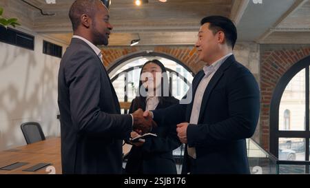 Trois personnes multiraciales d'affaires dans le bureau deux hommes d'affaires hommes d'affaires africains homme d'affaires asiatique Corée homme gars parlant poignée de main saluant succès deal Banque D'Images