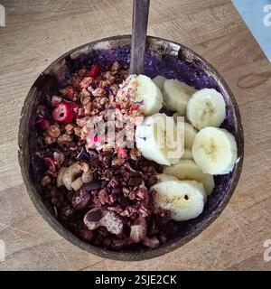 Un bol de smoothie coloré garni de granola, de banane fraîche et de diverses garnitures, parfait pour un petit déjeuner sain Banque D'Images