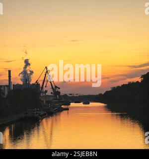 Une scène fluviale sereine et tranquille avec des silhouettes industrielles magnifiquement placées contre un coucher de soleil vibrant Hannover Mittellandkanal Banque D'Images