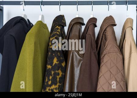 Une rangée de manteaux d'automne, d'hiver et de printemps dans des tons terreux accrochés sur un porte-vêtements élégant. Banque D'Images