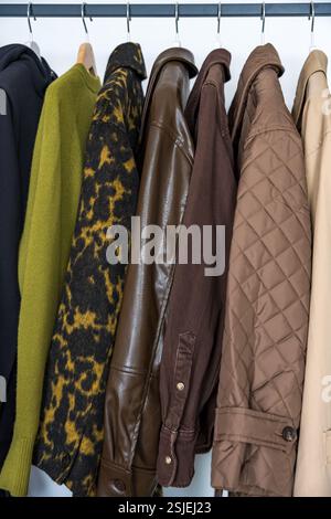 Une rangée de manteaux d'automne et de printemps dans des tons terreux accrochés sur un porte-vêtements élégant. Pleine longueur Banque D'Images