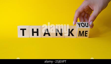Merci ou moi symbole. La main d'homme d'affaires tourne les cubes et change les mots Merci de vous remercier. Beau fond jaune. Business and Thanks concept Banque D'Images