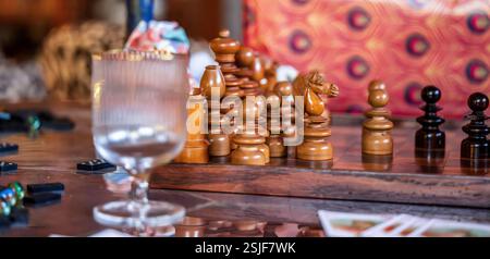 Jeu d'échecs artistique avec dominos, cartes à jouer et verres sur une table élégante Banque D'Images
