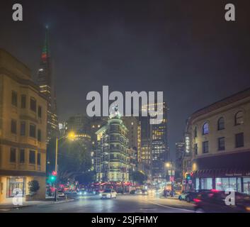 Un paysage urbain nocturne de San Francisco, avec une intersection de rues animées avec l'emblématique Transamerica Pyramid, se dresse en arrière-plan. Banque D'Images