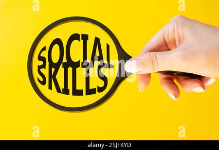 Symbole de compétences sociales. Mots conceptuels compétences sociales sur la loupe. Beau fond jaune. Main d'homme d'affaires. Compétences commerciales et sociales Banque D'Images
