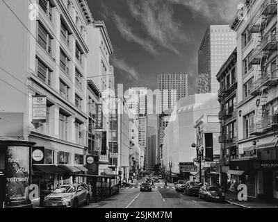 L'image capture une scène de rue animée de San Francisco, la ligne avec des voitures et des bus sur la route, avec quelques piétons marchant sur le trottoir. Banque D'Images