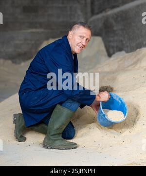 Portrait de fermier accroupi au tas de farine de maïs Banque D'Images