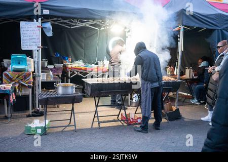 Les gens cuisinent sur un bar-b-que dans la rue du sud de Londres. Banque D'Images