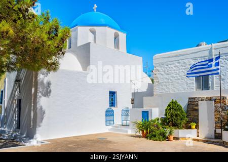 Église sur la place avec drapeau grec dans le village de Lagada, île d'Amorgos, Cyclades, Grèce Banque D'Images