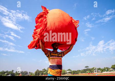 Un ouvrier porte un tissu teint sur sa tête alors qu'il se rend à l'usine après qu'elle a séché. Narsingdi, Bangladesh. Banque D'Images