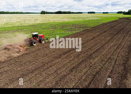 Une grande machine agricole cultive la terre. La vue du dessus. Labourage de terres pour la plantation de cultures. Photos de la vue de l'oiseau avec un quadc Banque D'Images