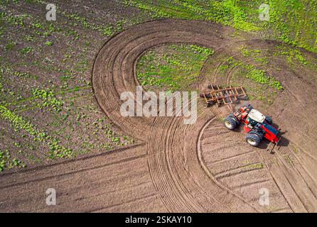 Une grande machine agricole cultive la terre. La vue du dessus. Labourage de terres pour la plantation de cultures. Photos de la vue de l'oiseau avec un quadc Banque D'Images