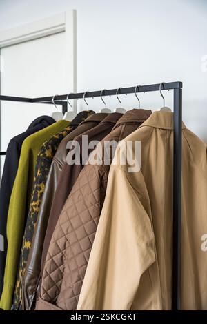 Une rangée d'automne, manteaux de printemps dans des tons terreux suspendus sur un porte-vêtements élégant Banque D'Images