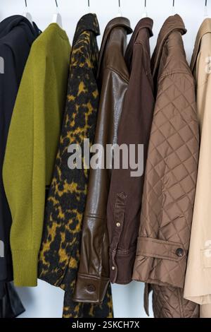 Une rangée de manteaux d'automne, d'hiver et de printemps dans des tons terreux accrochés sur un porte-vêtements élégant. Banque D'Images