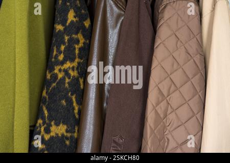 Une rangée de manteaux d'automne, d'hiver, de printemps dans des tons terreux accrochés sur un porte-vêtements élégant. Banque D'Images