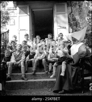 Buben sitzen auf der Treppe, Mädchen auf dem Schoss der Nonnen # garçons assis sur les marches, filles sur le genou de la religieuse #-- Osterfeier im Orphelinat du Servan, Lausanne 1946#Pâques à Orphelinat du Servan, Lausanne 1946- RDB BY DUKAS Banque D'Images