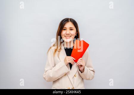 Fille de Taïwan tenant une enveloppe rouge avec de l'argent, paquet rouge du nouvel an lunaire avec argent, bonus et concept de salaire - succès financier et richesse Banque D'Images