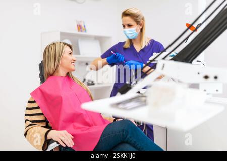 Dentiste heureux et patient parlant et souriant. Examen de dentiste à la clinique moderne de dentiste. Banque D'Images