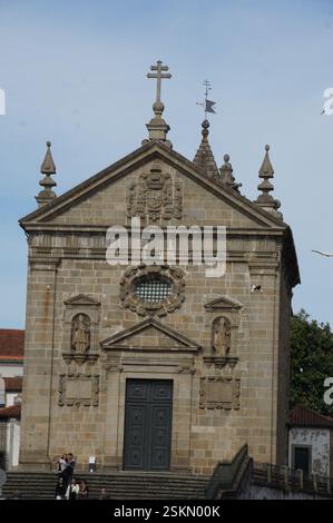 Façade d'église en pierre ornée à Braga, Portugal. Des sculptures complexes, des statues et une croix imposante ornent le bâtiment. Chef-d'œuvre architectural reflet Banque D'Images