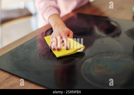 une fille en gants de caoutchouc jaunes lave une cuisinière électrique Banque D'Images
