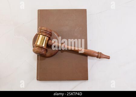 Un marteau en bois repose sur un livre de droit ouvert, représentant la justice et la profession juridique dans un environnement professionnel. Banque D'Images