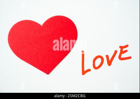 Mot amour, écrit à la main en rouge, à côté de cœurs rouges, sur une surface blanche. Banque D'Images