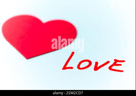 Mot amour, écrit à la main en rouge, à côté de cœurs rouges, sur une surface blanche. Banque D'Images