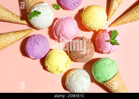 Cuillères à crème glacée assorties sur fond pastel rose, vue de dessus, espace de copie. De nombreuses cuillères à glace italienne bio avec des feuilles de menthe et de la gaufre c Banque D'Images