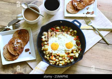 Petit-déjeuner rustique à la poêle avec œufs frits, pommes de terre, crêpes et café – scène brunch suspendu Banque D'Images