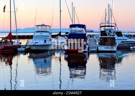 Bateaux amarrés à Marina au coucher du soleil avec Calm Water Reflections et mâts de voilier Banque D'Images