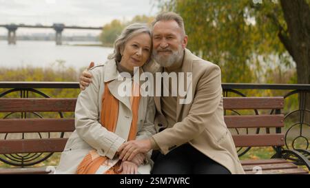 Retraité vieil homme adulte femme caucasienne liant affectueux couple d'amour mâle femelle embrassant sur le banc dans la ville de parc heureux famille d'âge moyen 60s Banque D'Images