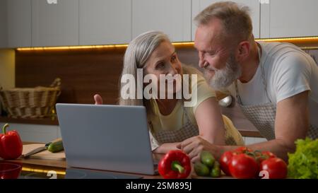 Famille caucasienne couple marié d'âge moyen femme et homme utilisent l'ordinateur portable achats en ligne acheter des aliments frais magasin Internet payer ordre mari retraité femme Banque D'Images
